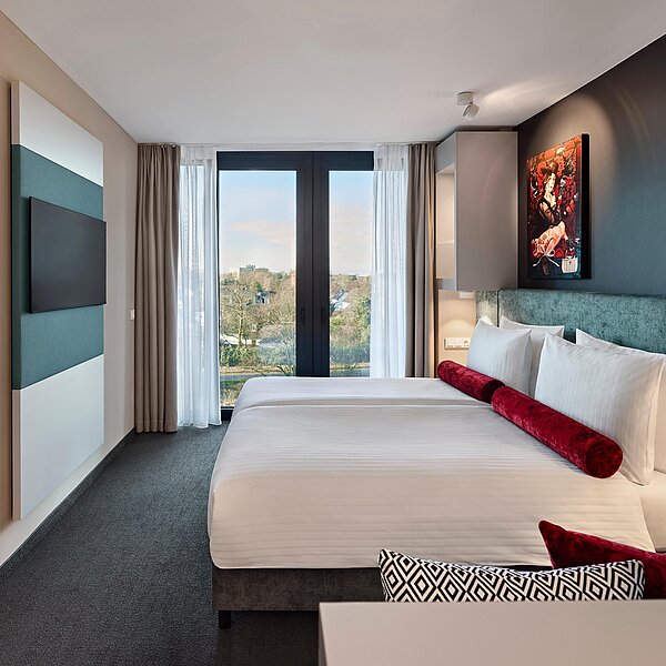 Modernes Hotelzimmer mit Doppelbett und Details in türkis, grau und rot